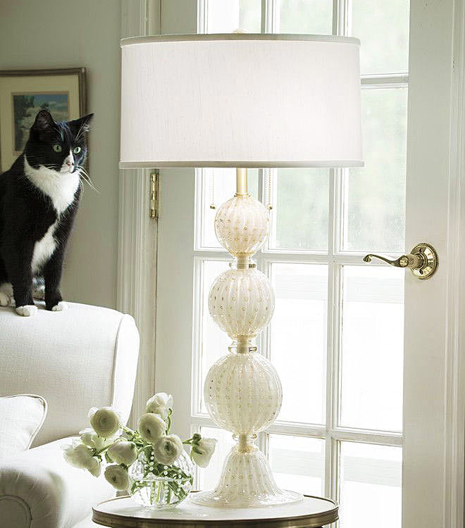 Decorative Crafts handmade Italian art glass table lamp with a white linen shade beside a sunlit window.