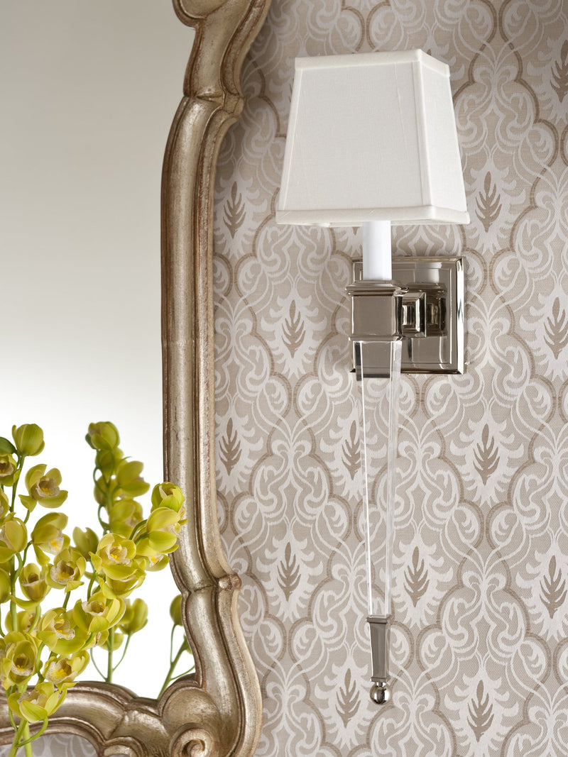 Decorative Crafts handmade Italian polished nickel wall sconce with white shade and clear glass stem beside an ornate mirror.