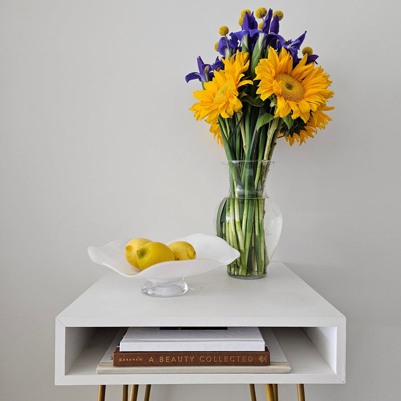 Decorative Crafts handmade Italian white art glass bowl styled with lemons on a contemporary side table with fresh flowers.