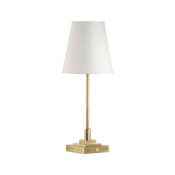 Table lamp with brass base and white shade on a white background