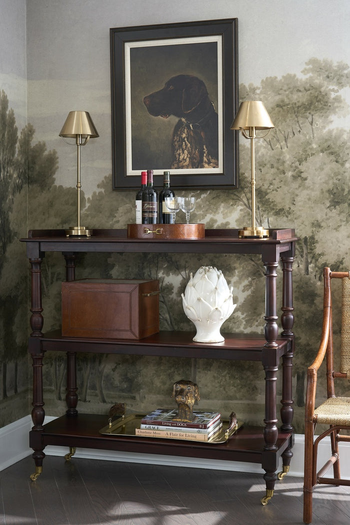 Dark wooden console table with decorative items against a wall with a large framed picture.