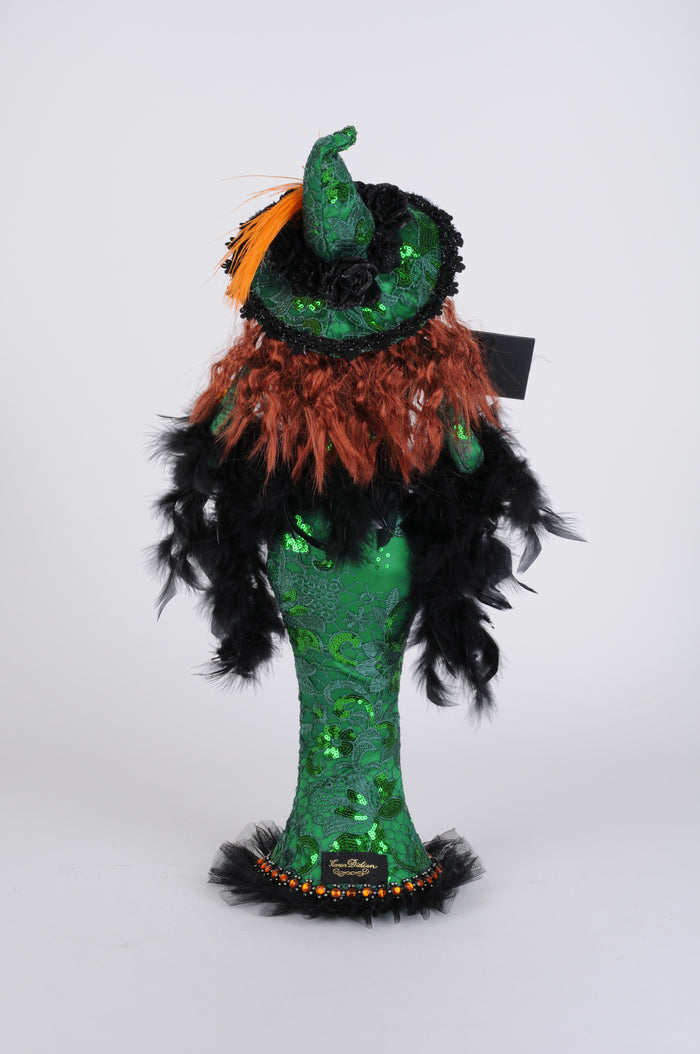 Halloween-themed plush toy with green sequin dress, black feathers, and orange accents on a white background.