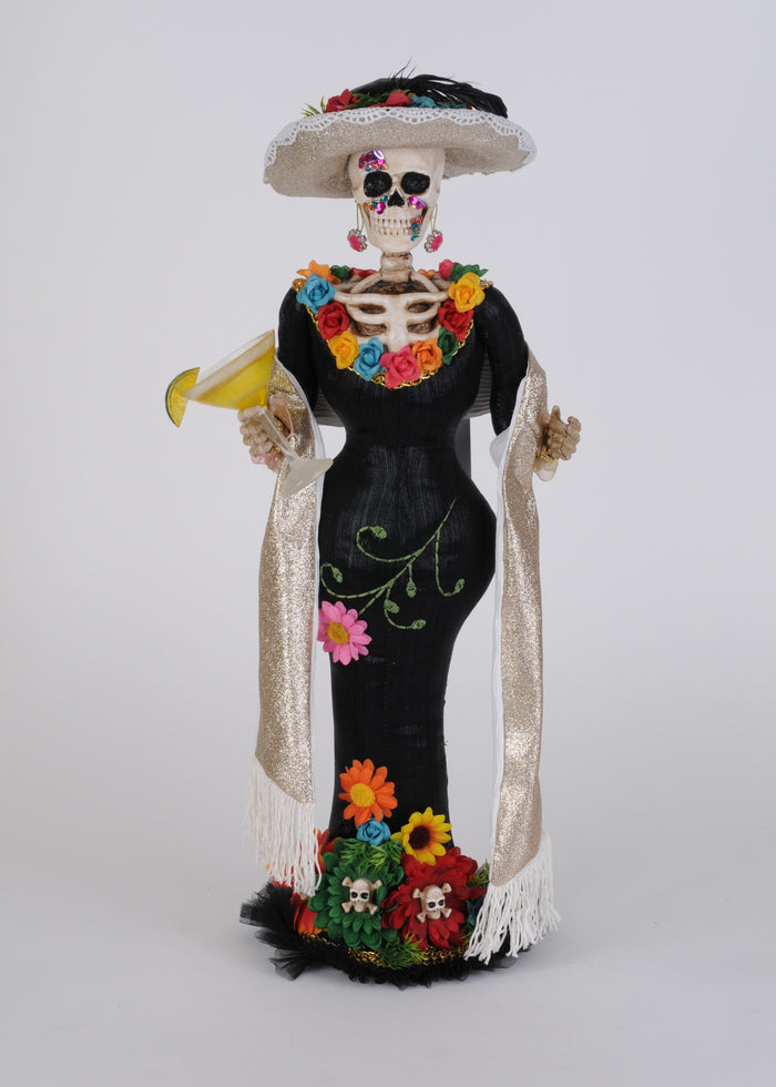 Decorative skeleton figure in a black dress with colorful flowers and a white hat on a light gray background