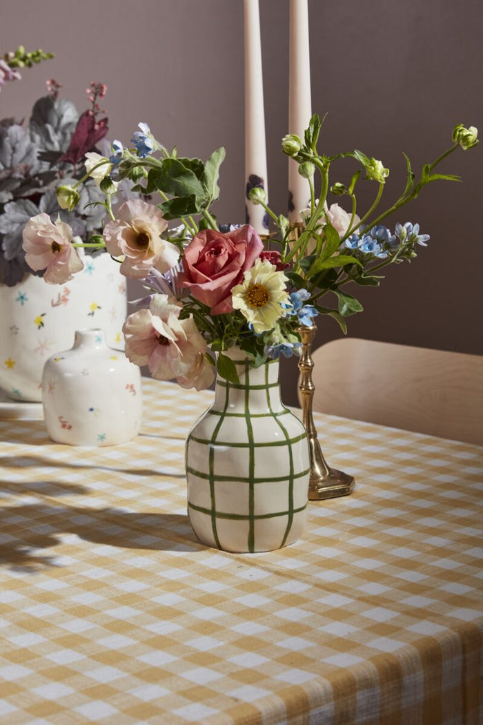 Floral arrangement in a checkered vase on a table with a checkered tablecloth