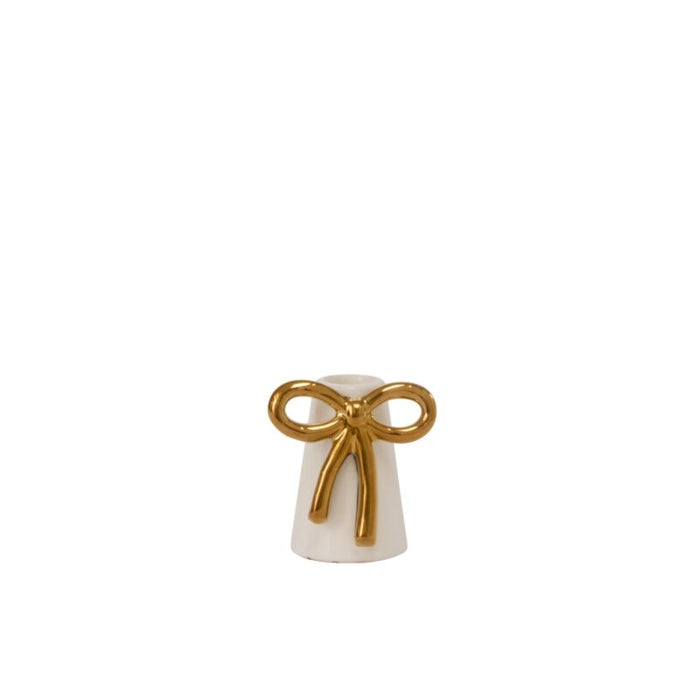 Small white ceramic bell with a gold bow on a white background
