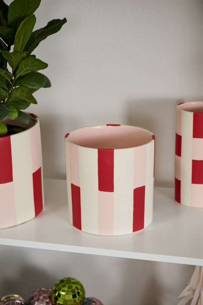 Three cylindrical ceramic planters with red and white striped design on a shelf.