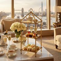 Gold three-tiered shelf with decorative top on a white background