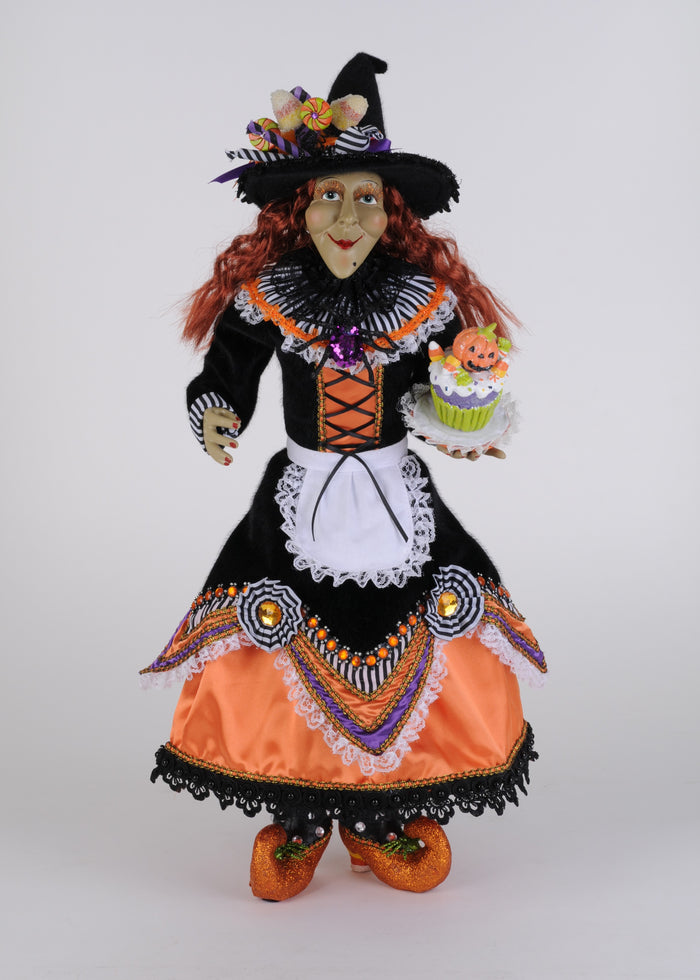 Halloween-themed doll in a witch costume with orange and black dress on a white background