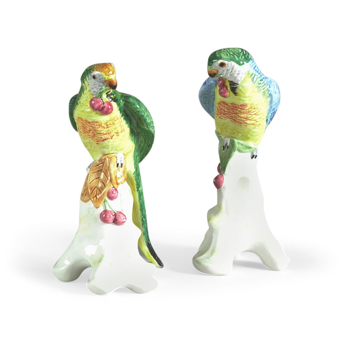 Two ceramic parrot figurines on white stands with a white background