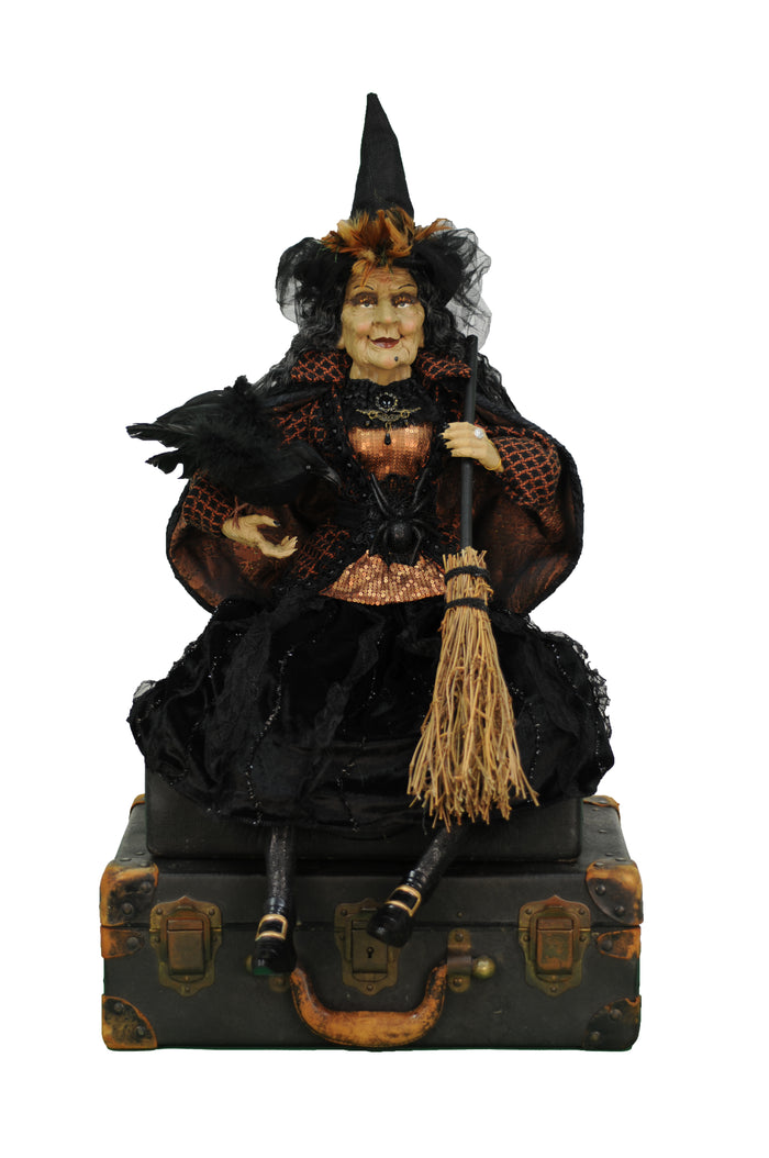 Decorative figurine of a witch with a black cat and broom on a suitcase, on a white background