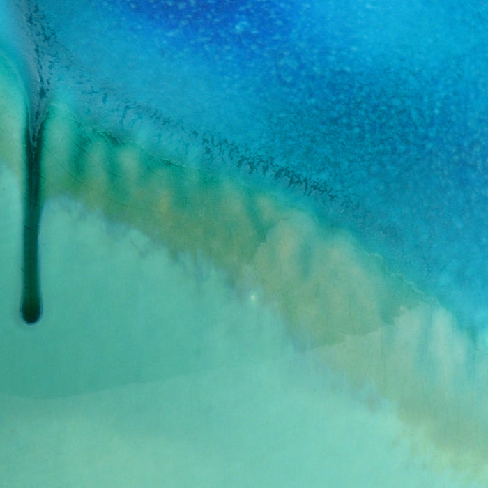 Close-up of a blue and green surface with a drop of water.