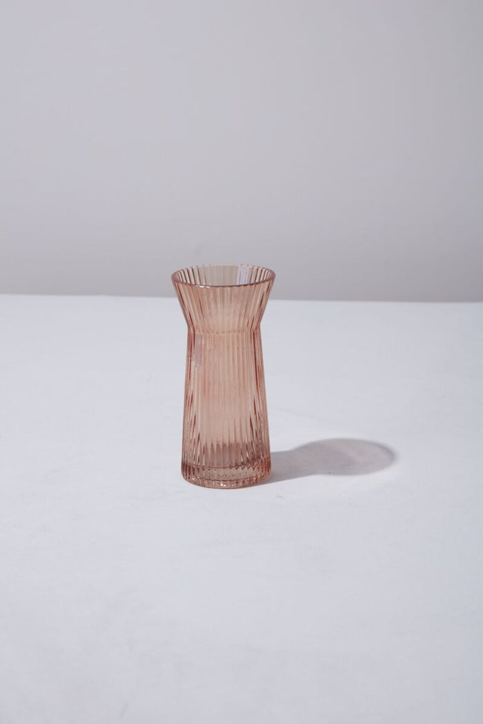 Pink glass vase on a white surface with a light gray background