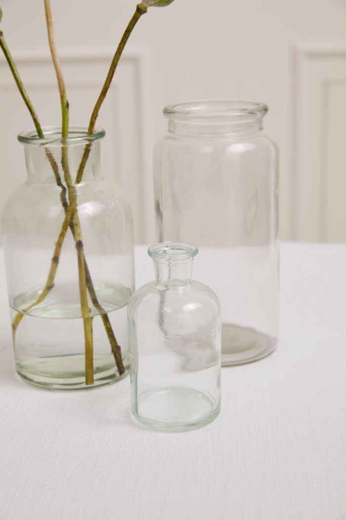 Three clear glass vases on a white surface with a plain background