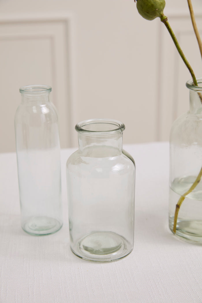 Three clear glass bottles on a white surface with a neutral background