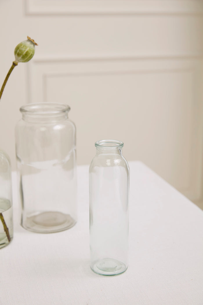 Two clear glass bottles on a white surface with a neutral background