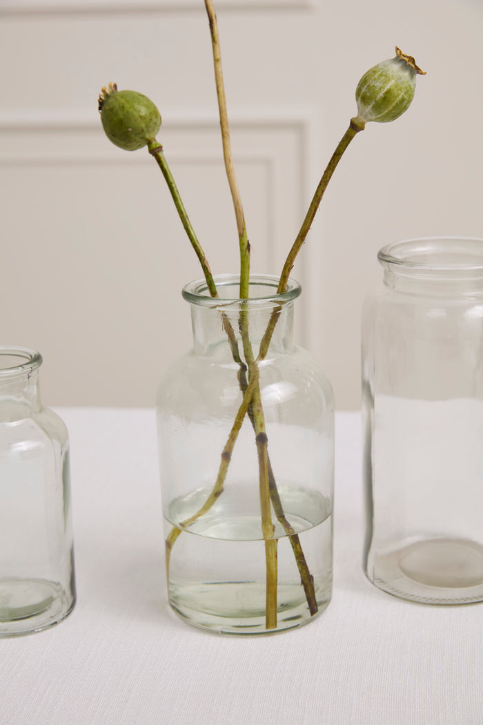 Clear glass vase with dried plants on a white surface