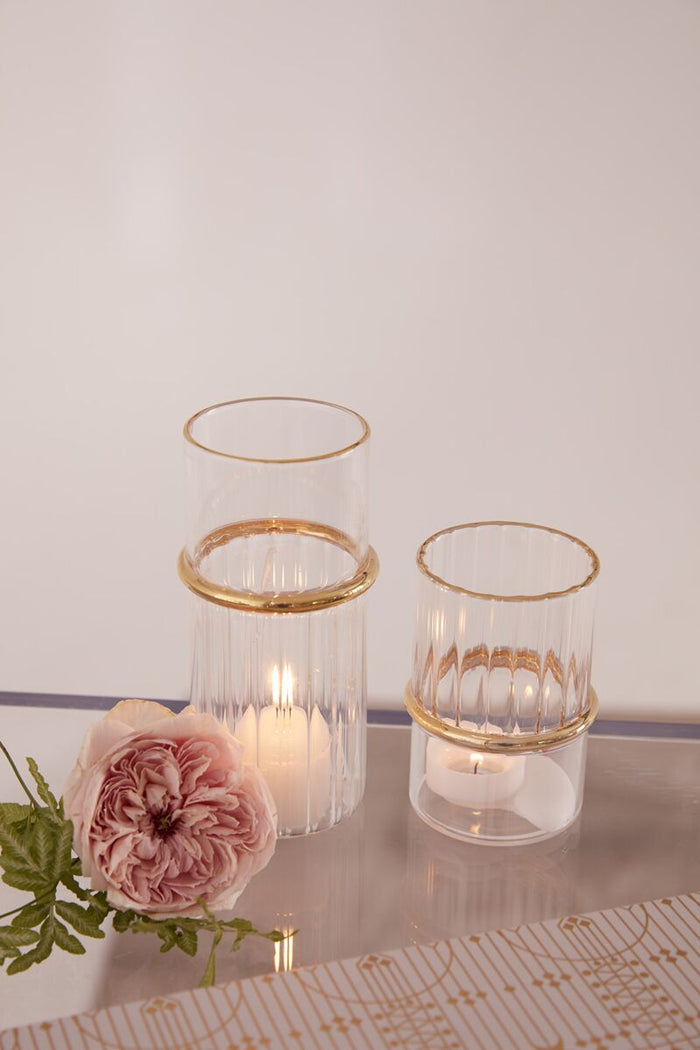 Two glass candle holders with gold bases on a light gray background