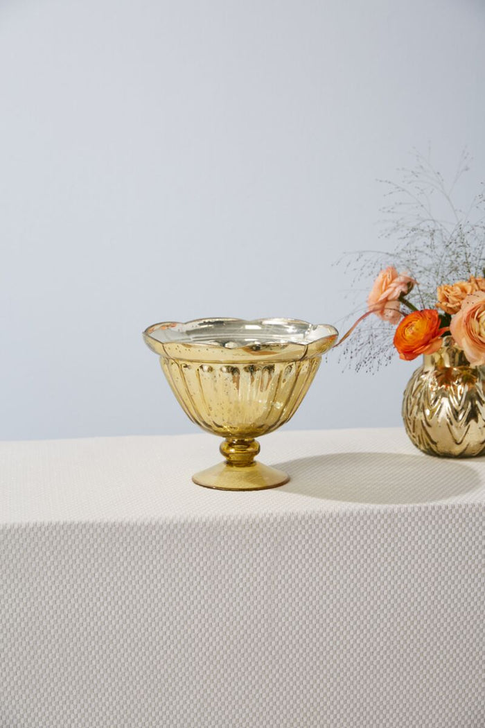 Gold decorative bowl on a white surface with a light blue background