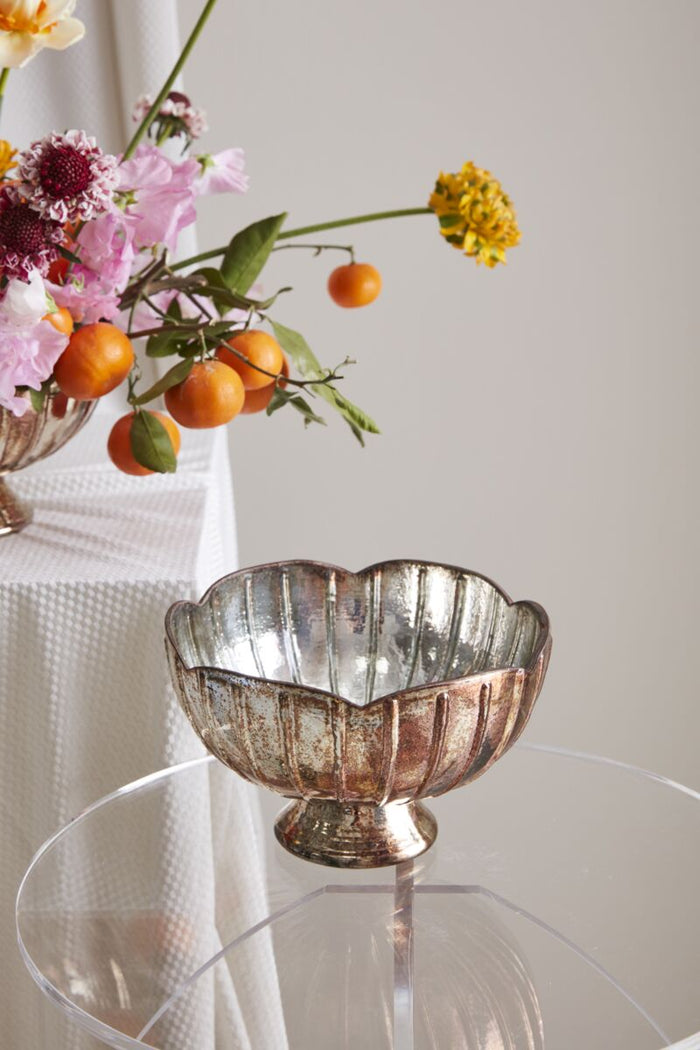 Decorative glass bowl with flowers and fruits on a white surface
