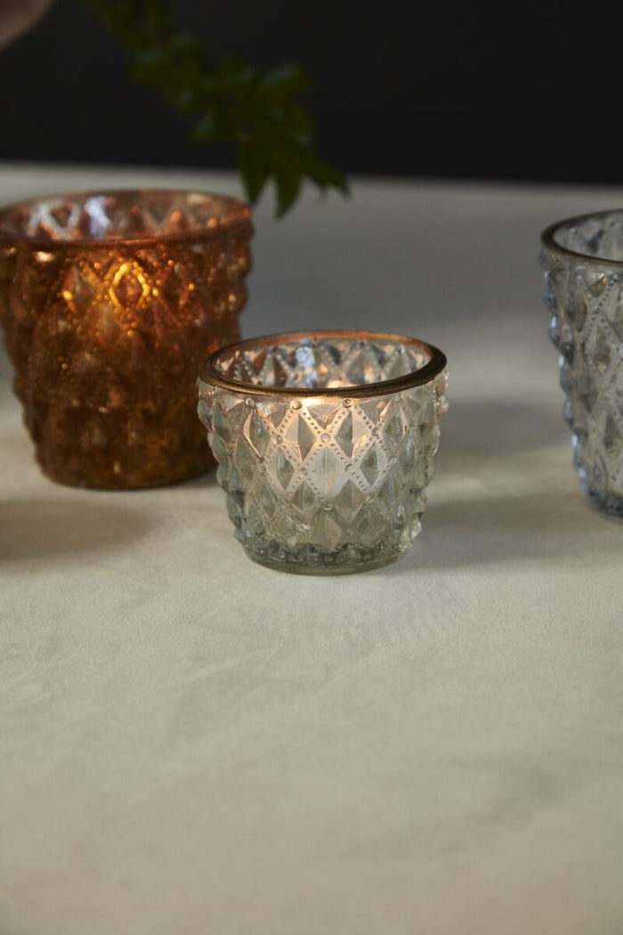 Three decorative glass candle holders on a neutral surface.