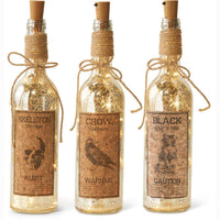 Three decorative bottles with labels and string lights on a white background