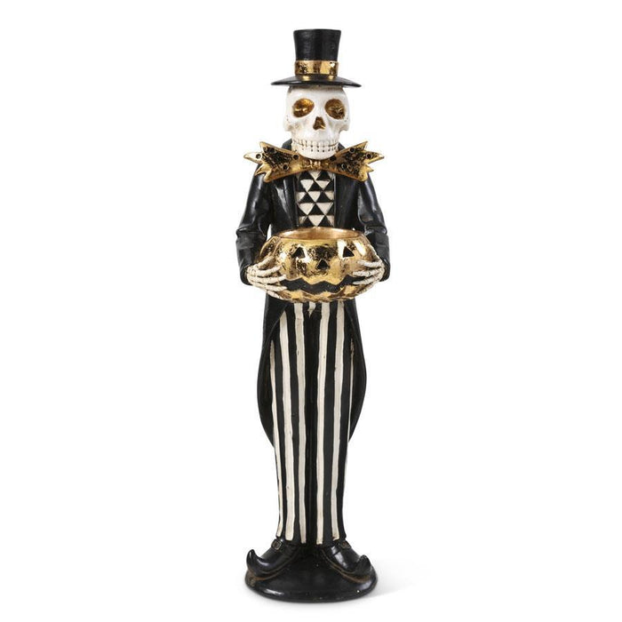 Skeleton figure in a top hat and black and white striped suit holding a pumpkin on a white background