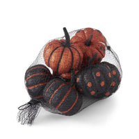 Decorative pumpkins in a black mesh bag on a white background