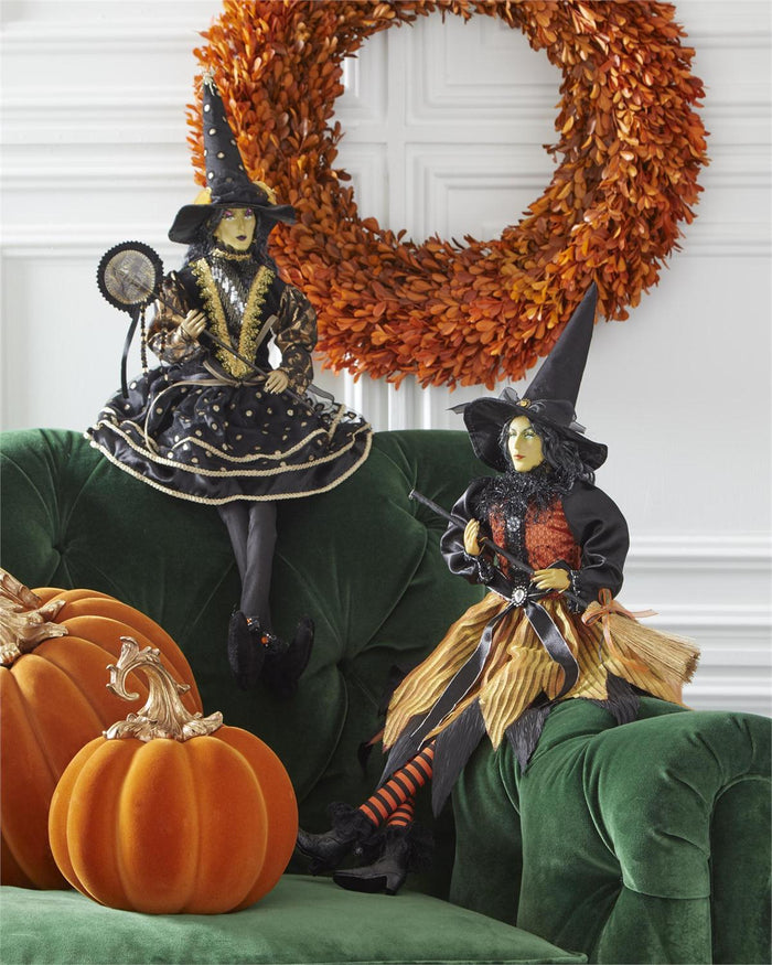 Halloween-themed decorations with witches, pumpkins, and a wreath on a green couch.