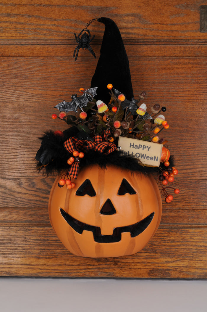 Decorative Halloween pumpkin with witch hat, candy corn, and spider on a wooden background