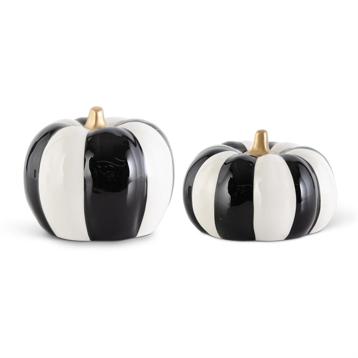 Set of two ceramic pumpkins with glossy black and white striped panels and small gold stems on a white background.