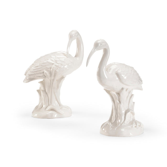 Two white ceramic flamingo figurines on a white background