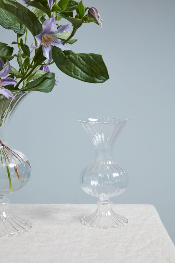 Clear glass vase on a light surface with a light gray background