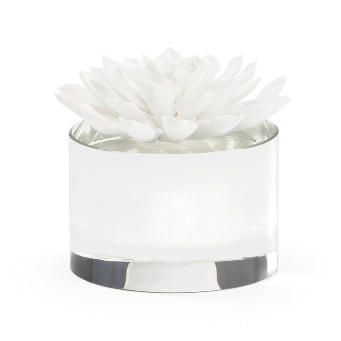 Clear glass candle holder with a white flower on a white background