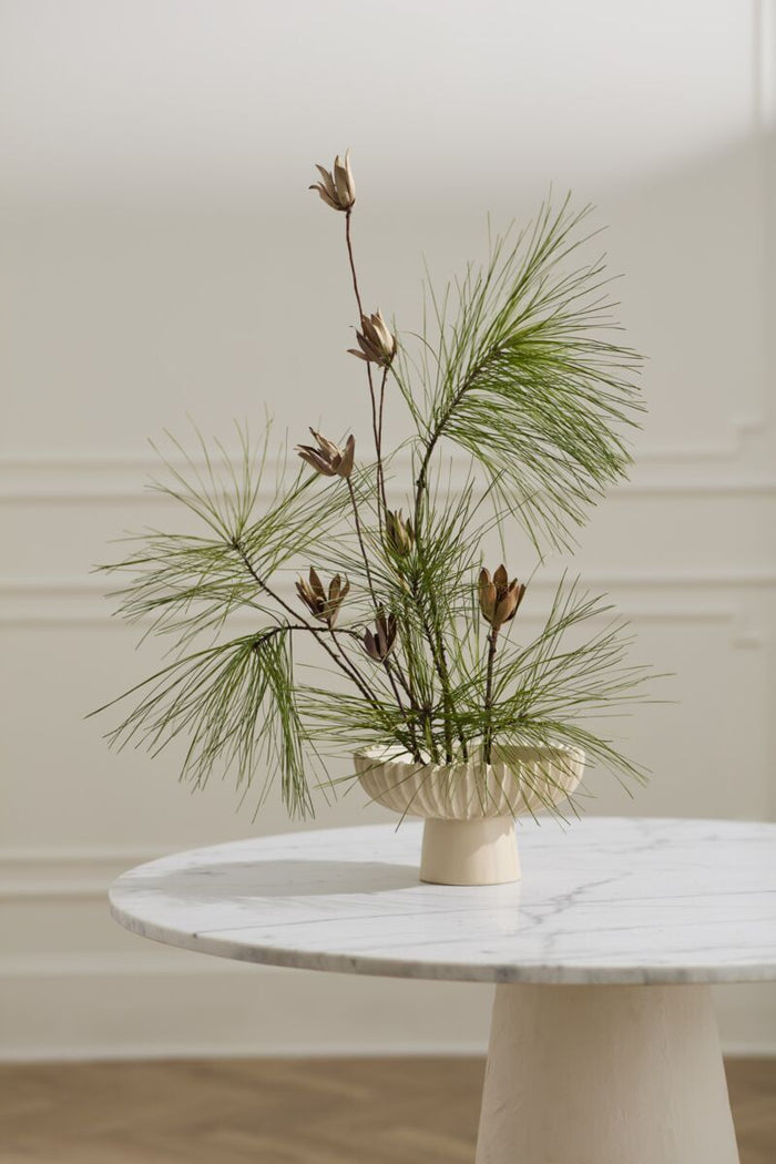 Decorative plant arrangement in a vase on a marble table with a neutral background