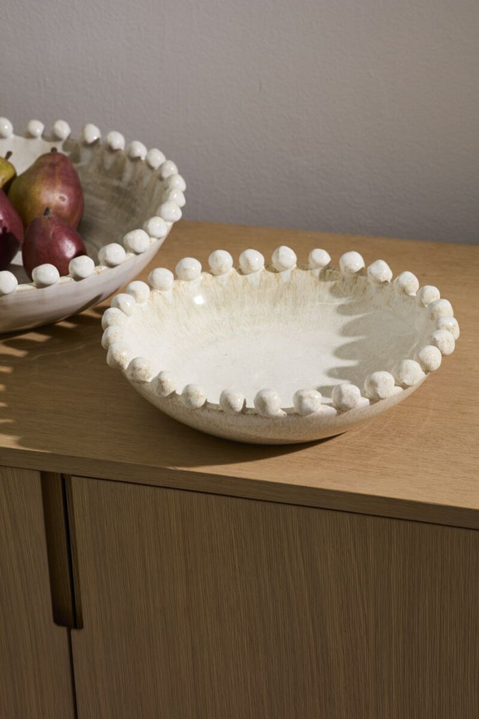 Two ceramic bowls with decorative edges on a wooden surface.