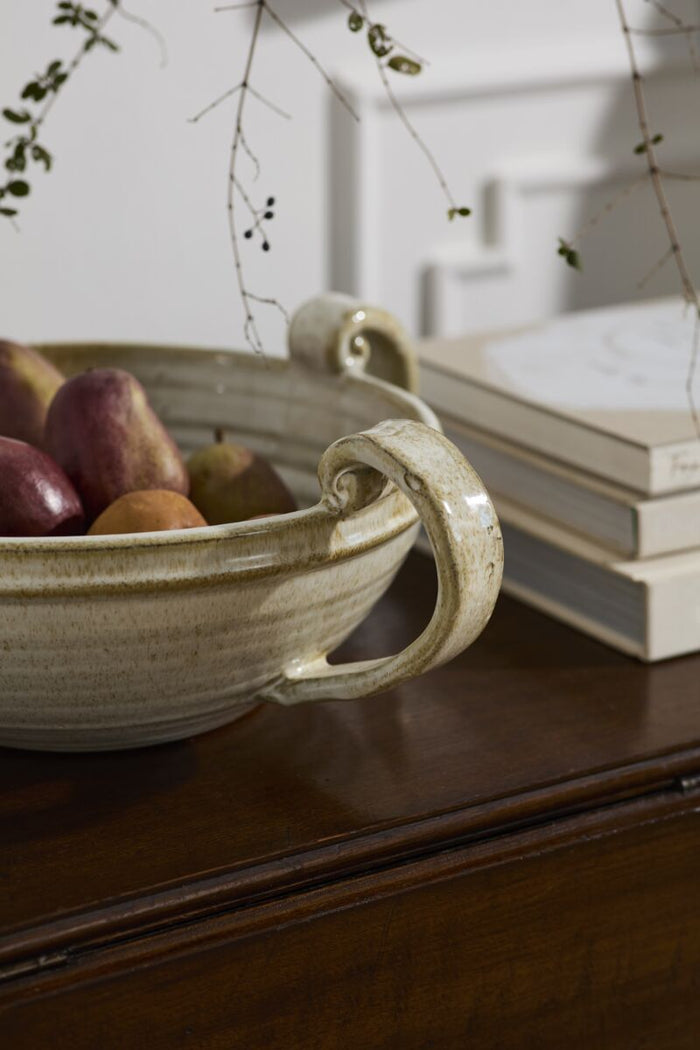 Decorative bowl with fruits on a wooden surface next to books