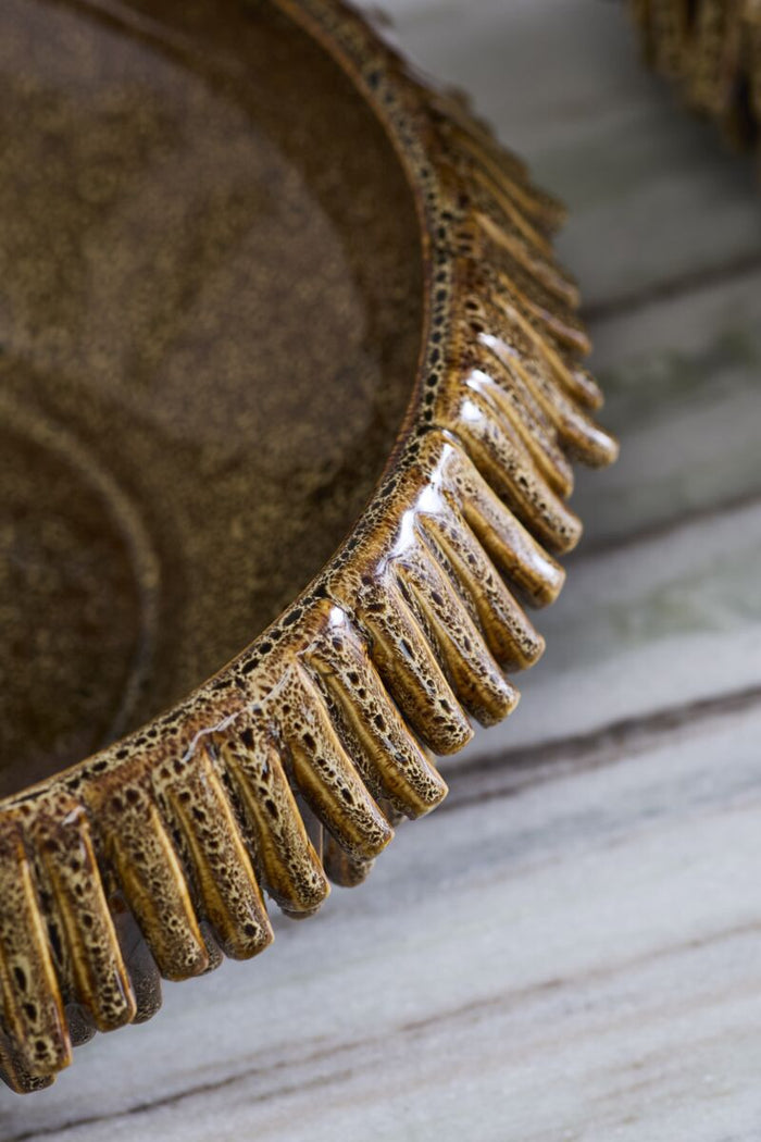 Close-up of a ceramic plate with textured rim on a marble surface