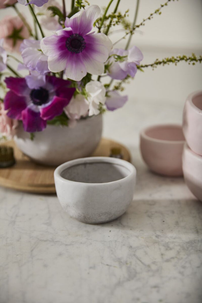 Ceramic bowls and a vase with flowers on a marble surface