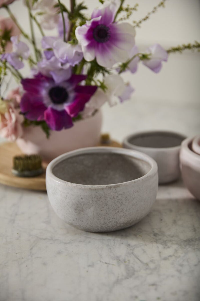 Concrete bowl on a marble surface with flowers in the background