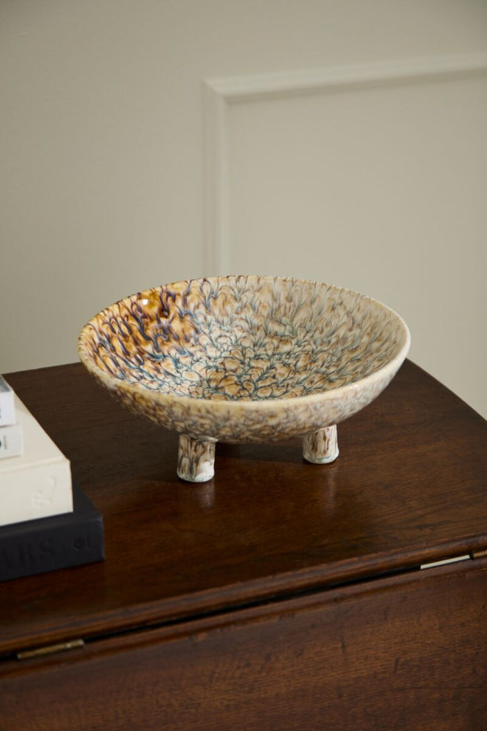 Decorative ceramic bowl on a wooden surface with a neutral background