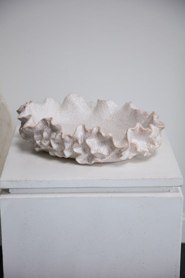 Decorative white coral-like object on a white pedestal against a gray background