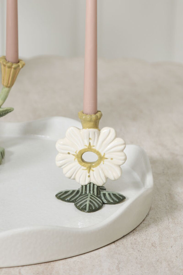 Decorative candle holder with a white flower design on a neutral background