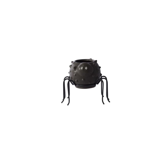 Black spider-shaped container with googly eyes on a white background