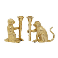Gold-toned aluminum monkey candle holders with two cyclindrical candle cups, facing each other on bamboo-like stems.