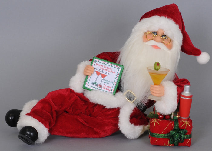 Santa Claus figurine holding a cocktail and a gift box on a gray background