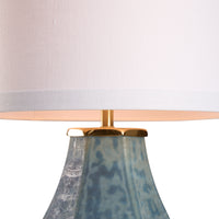Lamp with a white shade and textured blue base on a white background