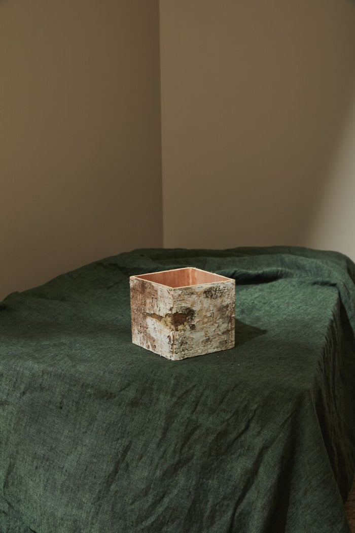 Square ceramic pot on a green surface with a plain background