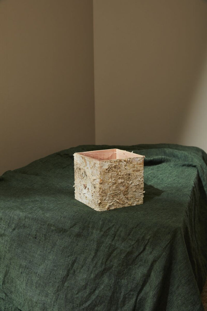 Square stone object on a green surface with a neutral background
