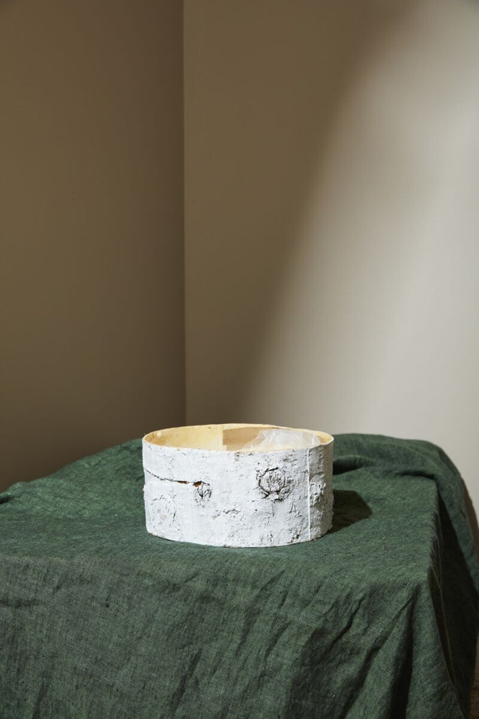 Birch bark bowl on a green cloth with a neutral wall background