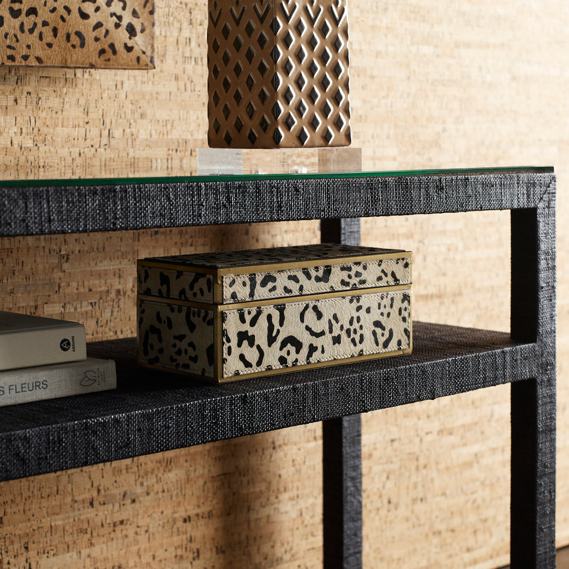 Decorative console table with leopard print boxes and books against a textured wall.